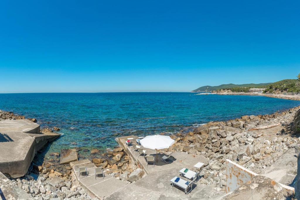 罗西尼亚诺马里蒂莫Villa Dell'Angelo 10, Emma Villas的海滩上设有白色的遮阳伞和椅子,