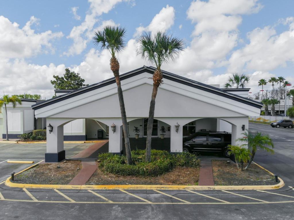 奥兰多Stayable Orlando at Florida Mall的一座建筑前有两棵棕榈树的停车场