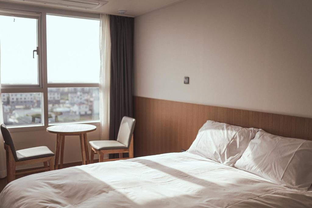 西归浦市Kenny Stay Jeju Mosulpo的卧室配有一张床和一张桌子及椅子