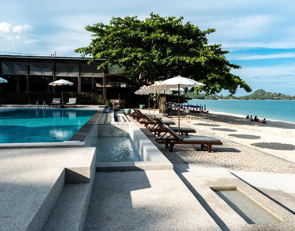 拉迈The Hive Hotel的海滩上带长椅和遮阳伞的游泳池