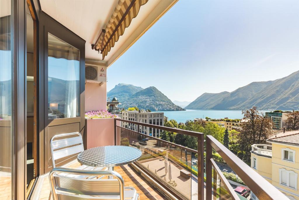 卢加诺Hotel Delfino Lugano的阳台配有桌椅,享有水景。