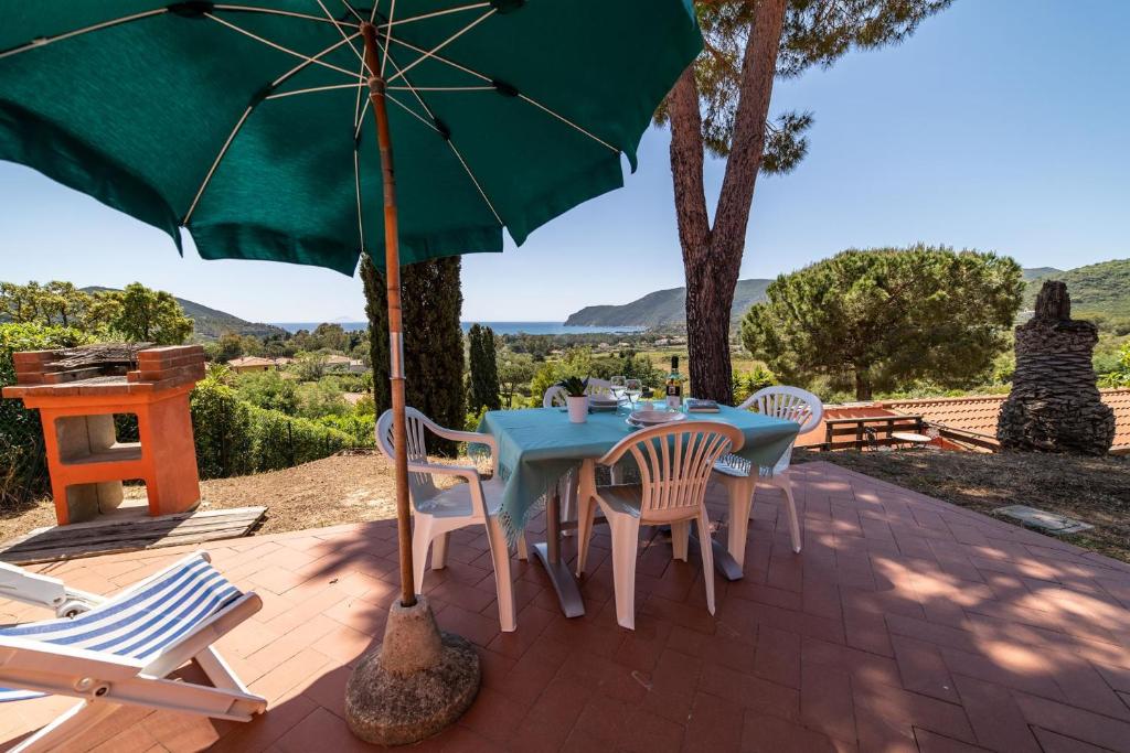 拉科纳Casa Rossa Lacona的露台配有桌椅和绿色遮阳伞