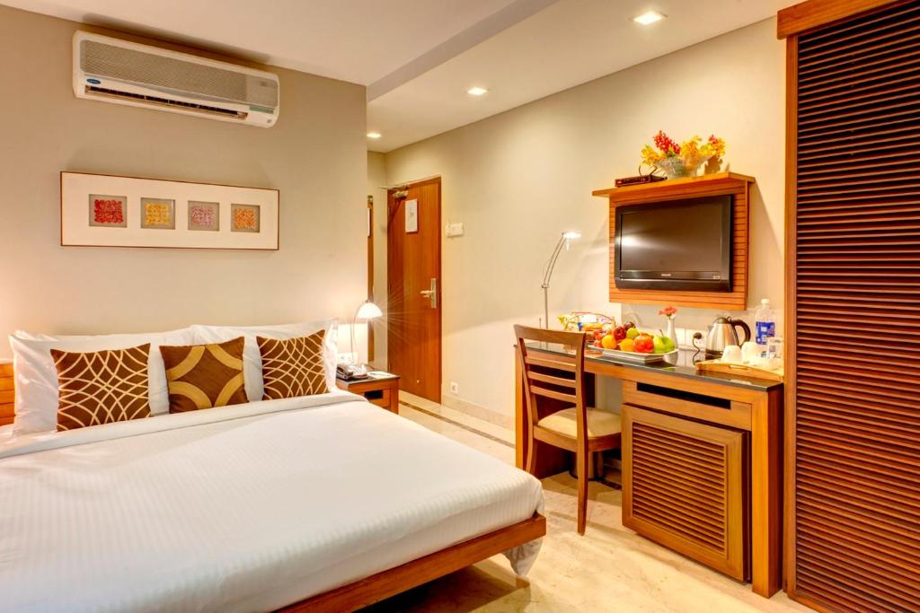 加尔各答幸运之家酒店的一间卧室配有一张床和一张书桌及电视