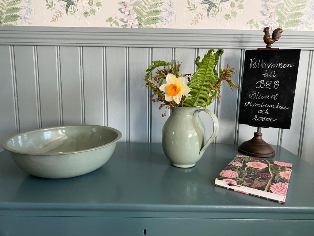 法尔肯贝里B&B Bland ormbunkar och rosor的一张桌子,上面有碗,花瓶和标志