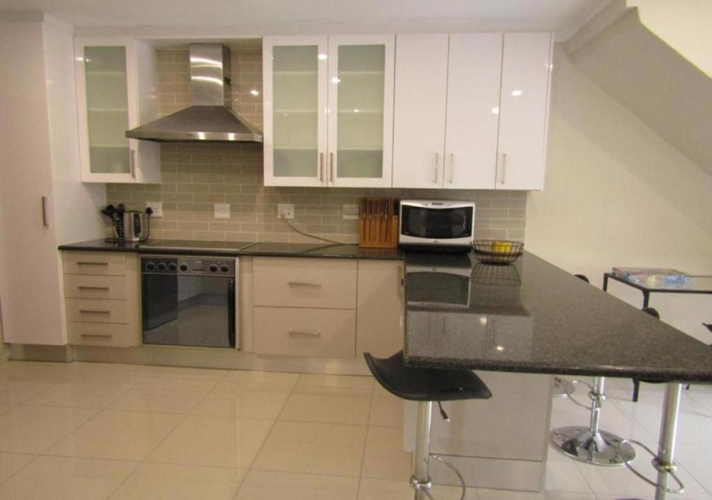 SandtonSunninghill Luxury Spacious Executive Penthouse的厨房配有白色橱柜和黑色台面