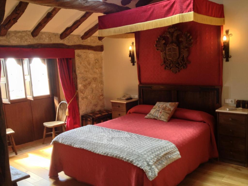 MaderueloHotel Rural El secreto del Castillo的一间卧室配有一张红色天蓬床