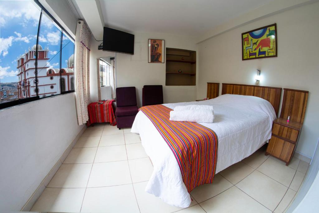 普诺Inka's Rest Hostel的酒店客房设有一张床和一个大窗户