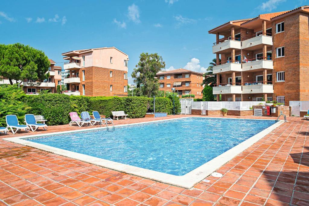 科马鲁加Pierre & Vacances Comarruga的一座带两把椅子的游泳池以及一座建筑