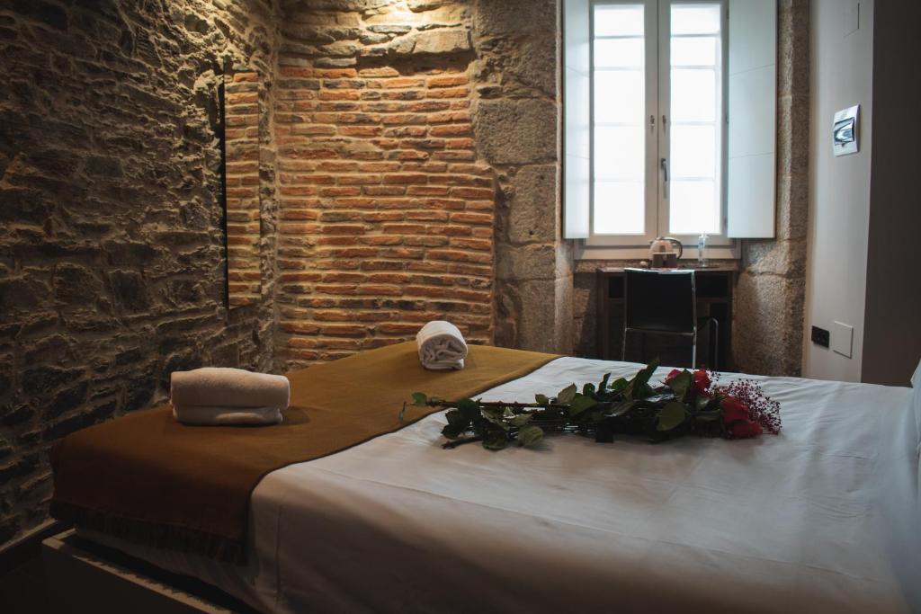 圣地亚哥－德孔波斯特拉潘诗恩阿卡萨度佩瑞格里诺酒店的一张带两条毛巾和鲜花的床