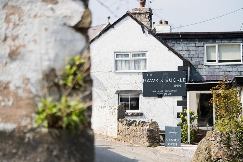 LlannefyddThe Hawk & Buckle Inn的前面有标志的白色建筑