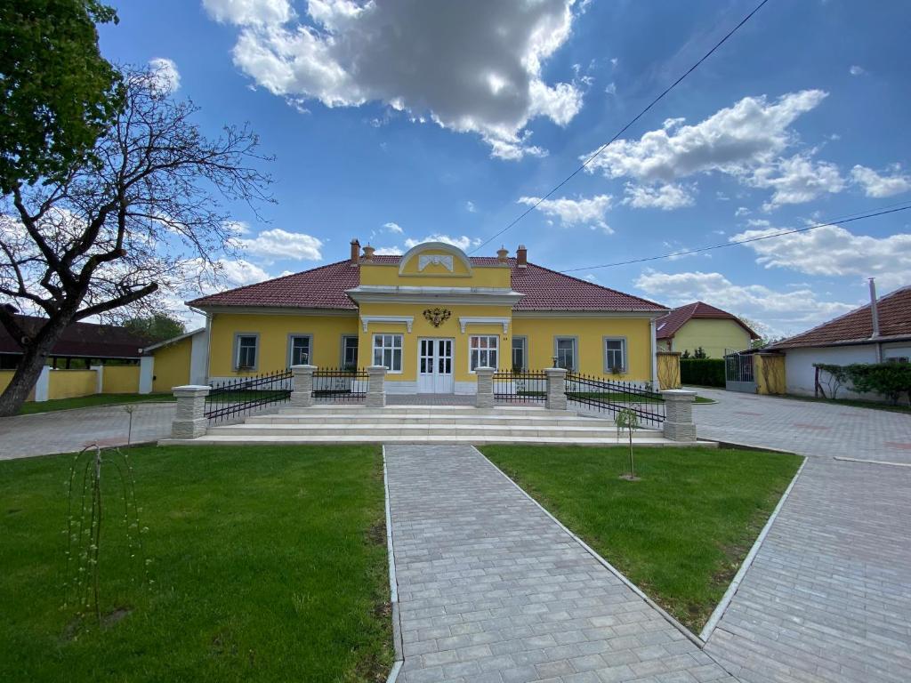 波罗斯洛Kúria Vendégház的前面有楼梯的黄色房子