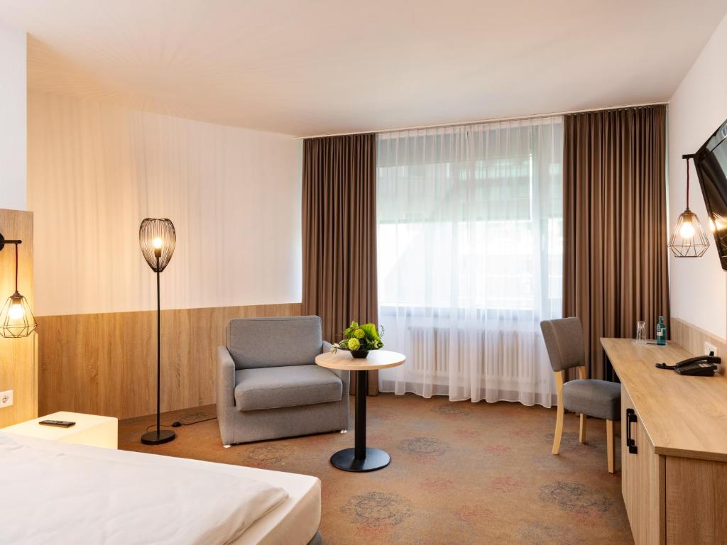 美因河畔法兰克福Plaza Hotel & Living Frankfurt的酒店的客房 - 带一张床、椅子和窗户