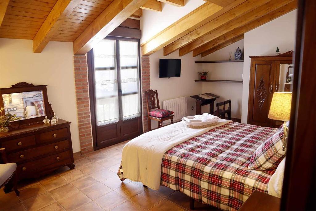 卢安科Casa Rural La Tayuela的一间卧室配有一张床、梳妆台和电视。
