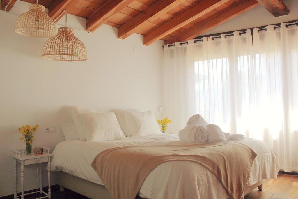 MontagutEl Niu Casa Rural的一间卧室配有一张带白色床单的床和一扇窗户。