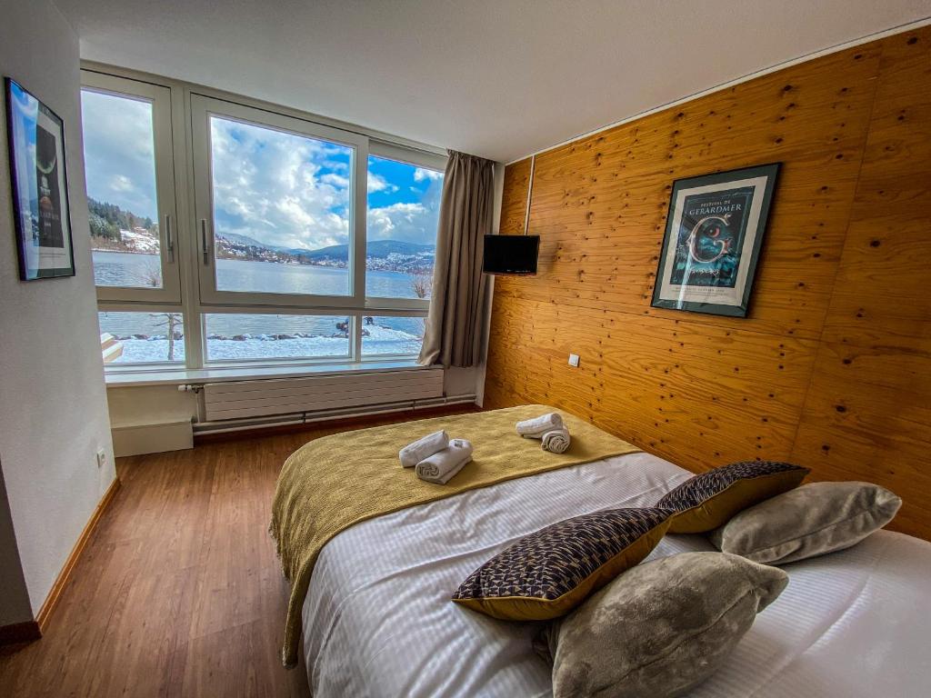 热拉梅Appart'Hôtel LIDO au bord de l'eau的一间卧室设有一张大床和大窗户