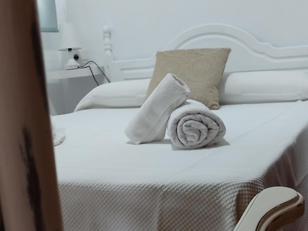 博罗尼亚Apartamentos Bolonia - M a n u e l a的一张白色的床,上面有一条可移动的毛巾