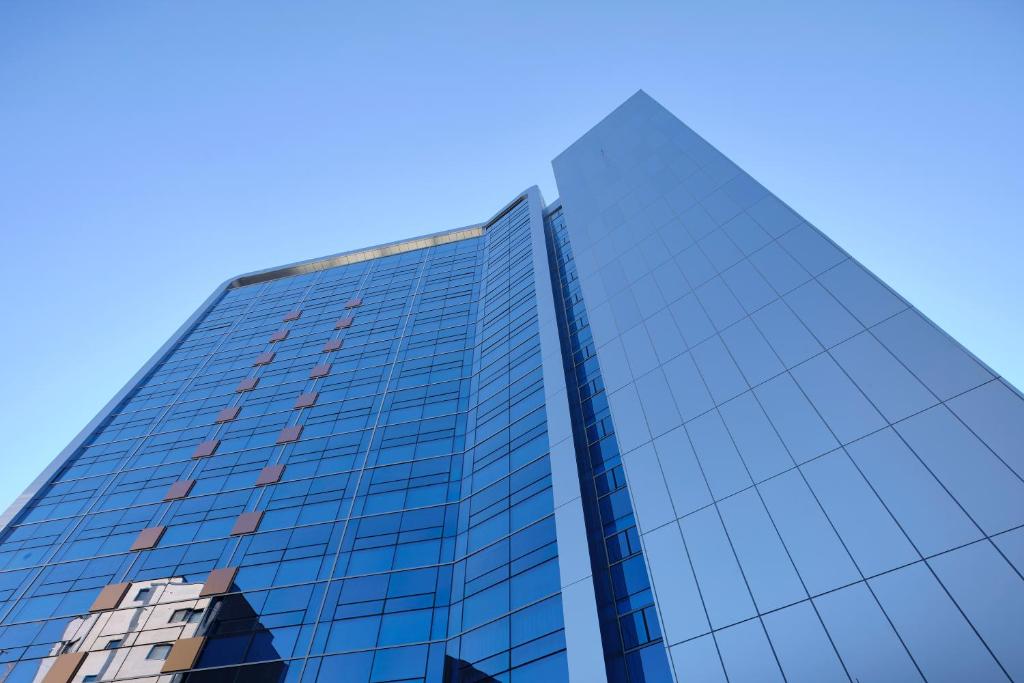 水原市S Stay Hotel的一座高大的玻璃建筑,背后是蓝天