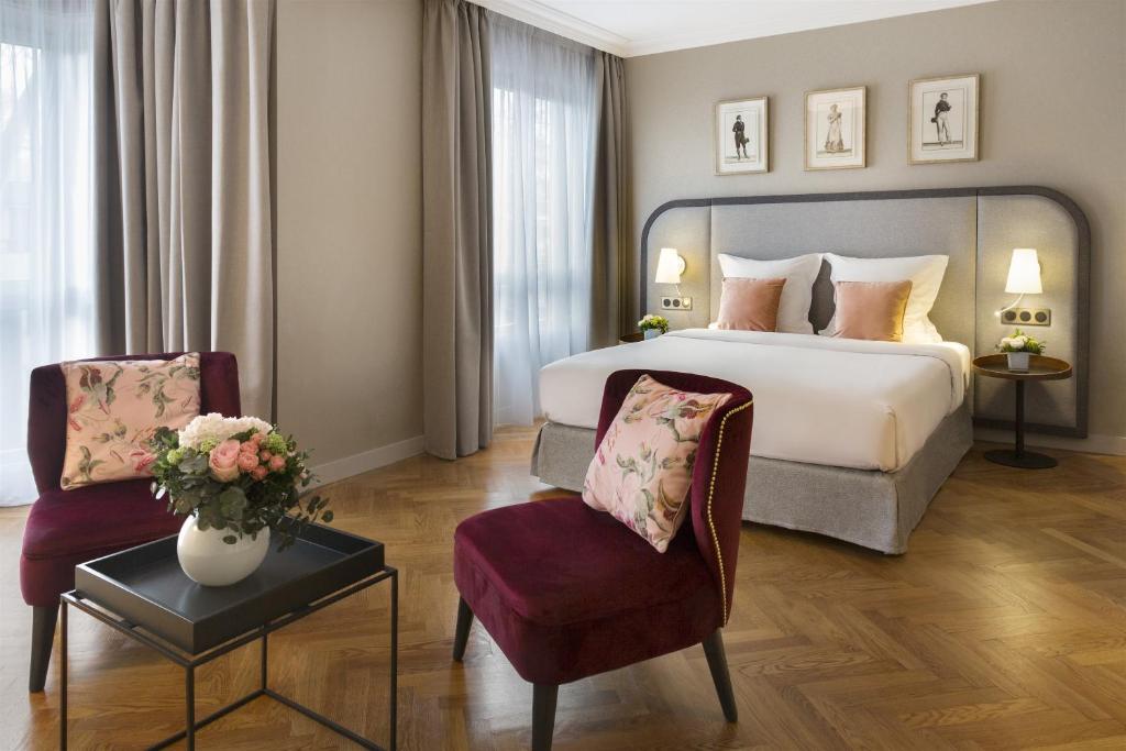 里昂里昂华威雷奥斯特公寓式酒店的酒店客房,配有一张床和两把椅子