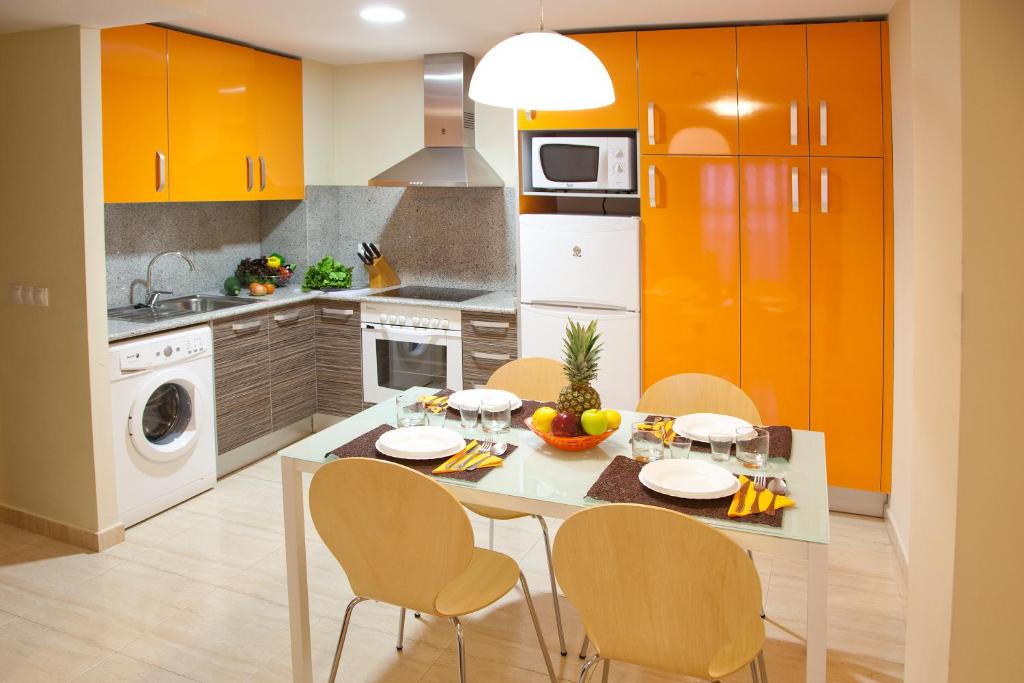 蒙塔尼约斯坎普布拉公寓式酒店的厨房配有橙色橱柜和桌椅