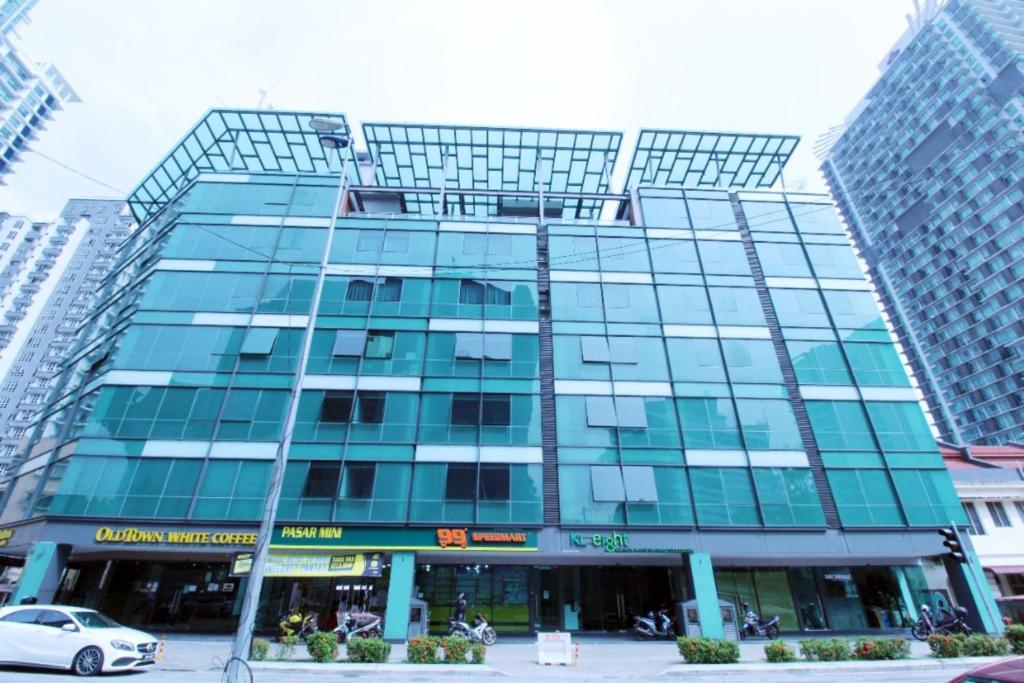吉隆坡KL Eight Suites Newly completed 2021的一座高大的玻璃建筑,前面有一辆汽车