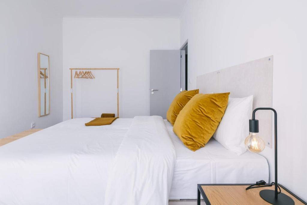 波尔图D&S - Family Apartments I的白色卧室配有一张白色大床和黄色枕头