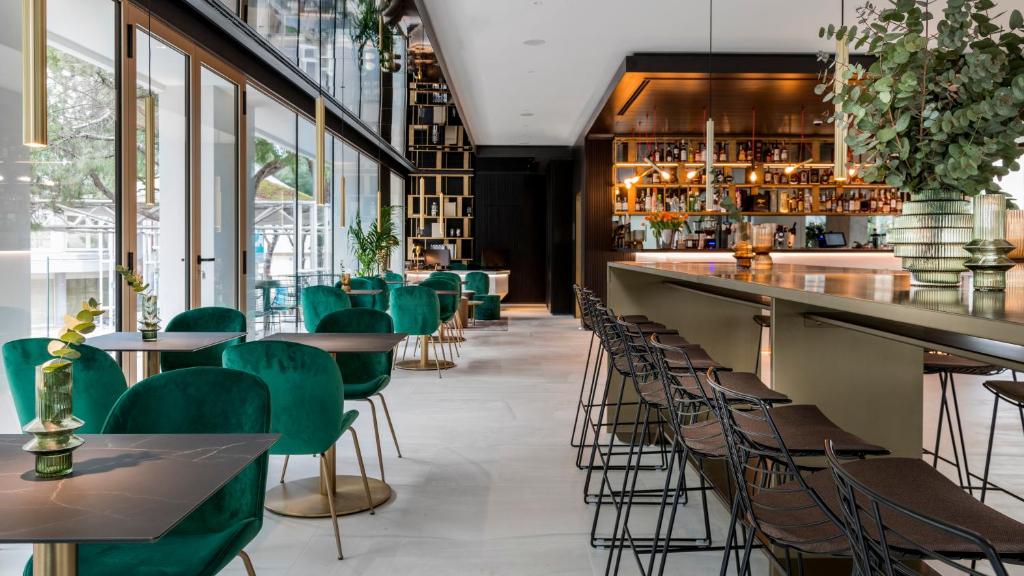 里乔内We Me Suite Hotel的一间设有绿色椅子的餐厅和一间酒吧