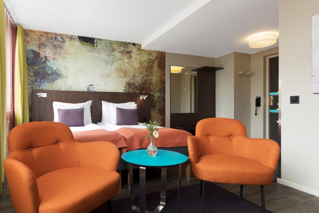 延雪平ProfilHotels Savoy的酒店客房,配有床和橙色椅子
