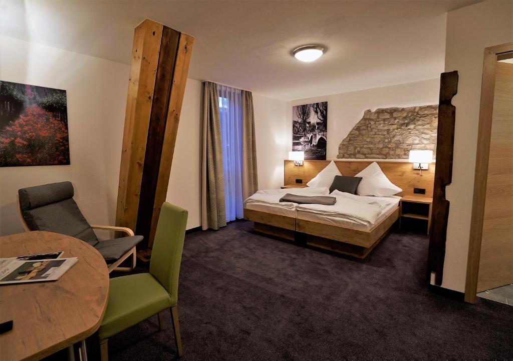 ForchtenbergKelterhotel Fröscher的酒店客房配有一张床铺和一张桌子。