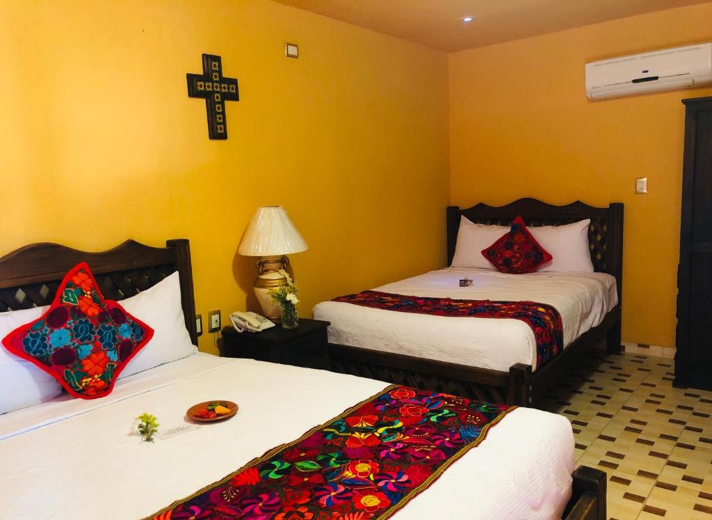 图斯特拉古铁雷斯Camino Mexicano Hotel & Resort的一间设有两张床的客房,墙上有一个十字架