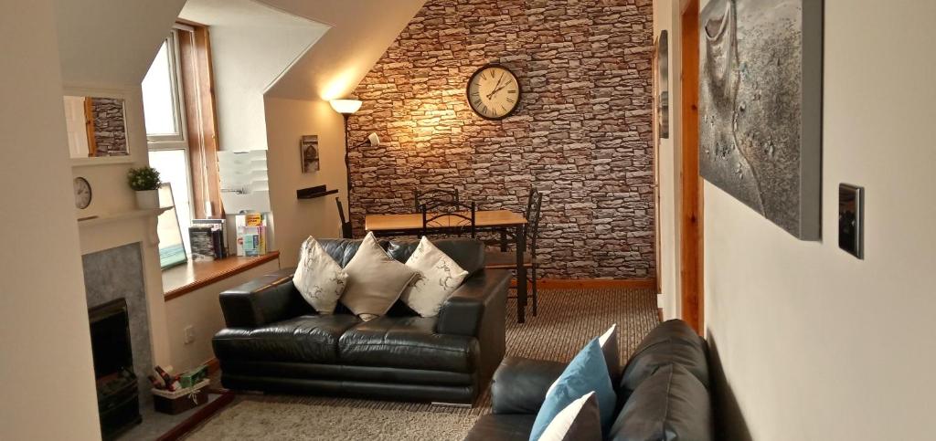 斯托诺韦Flat 14c Bayhead的客厅配有沙发和砖墙上的时钟