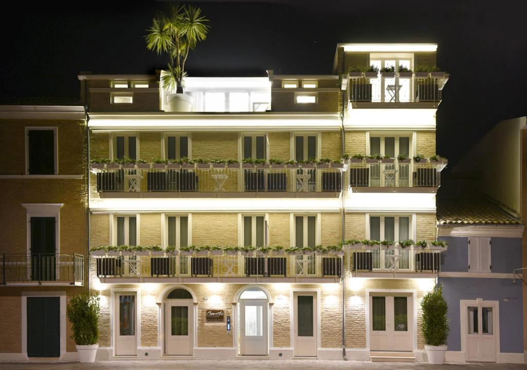 雷卡纳蒂港Opera Arte Suite Apartments的黄色的大建筑,晚上在阳台上种有植物