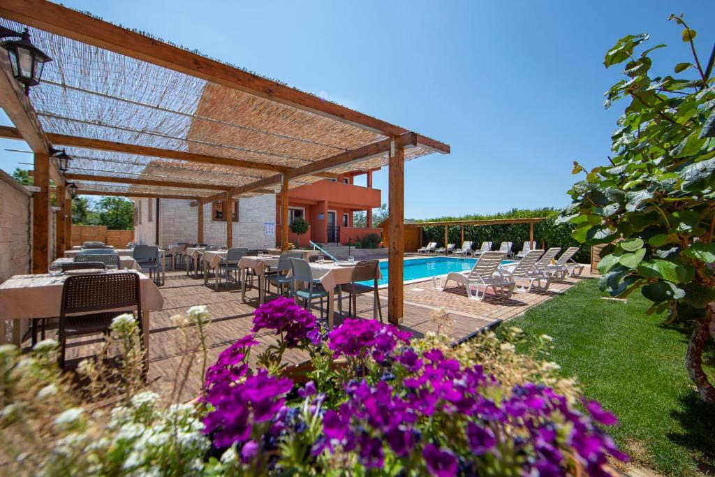 乌马格Hotel Natura Vilanija的一个带桌椅和紫色鲜花的庭院