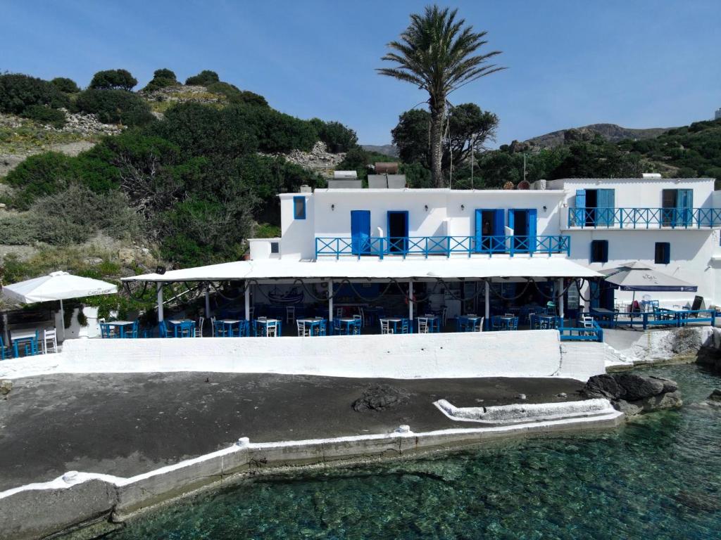 KeramesAgia Fotia Taverna的白色的建筑,水中摆放着蓝色的椅子