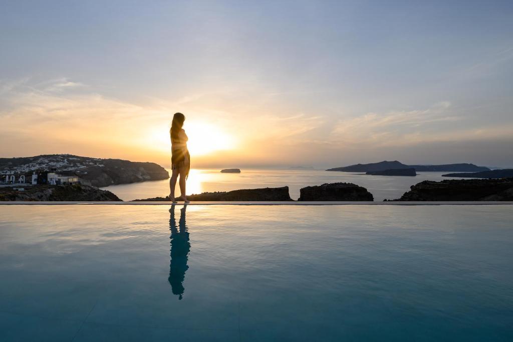 梅加洛克里Ambeli Sunset Villas的站在游泳池边欣赏日落的人