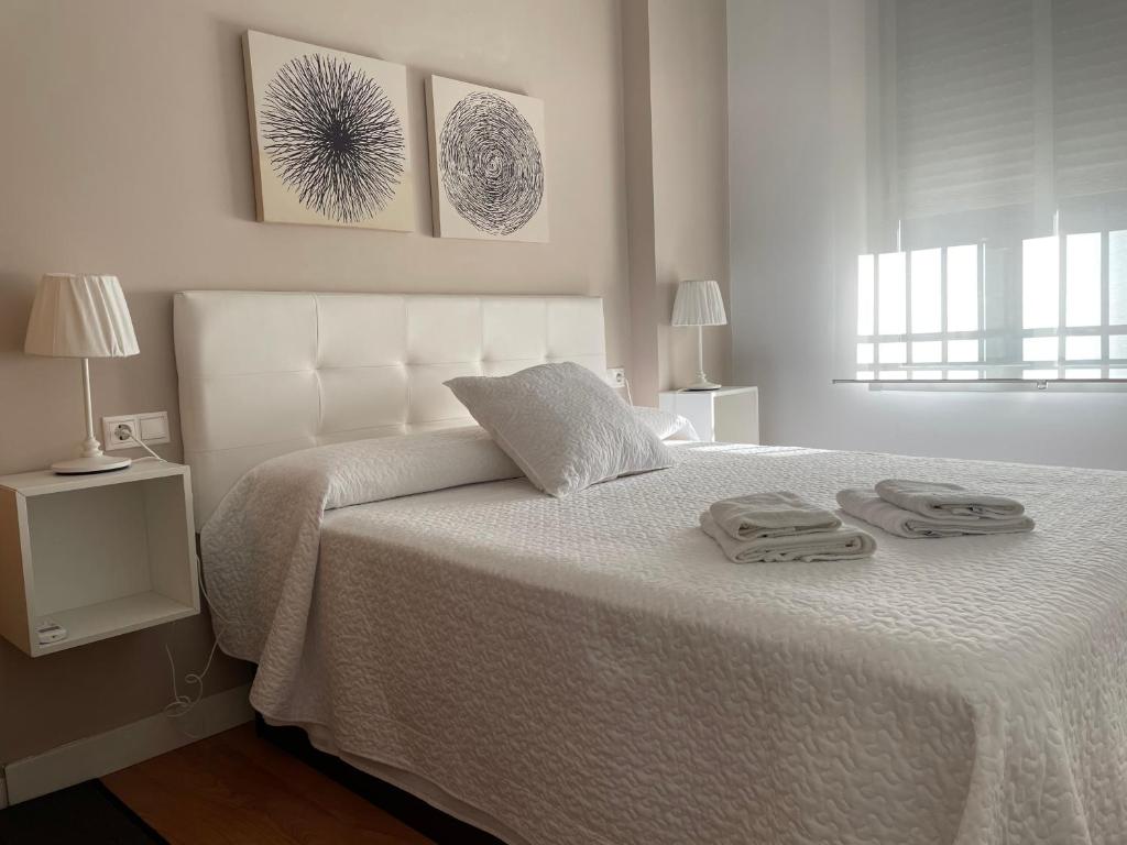 科尔多瓦Apartamento La Mezquita-Catedral的卧室配有白色的床和2条毛巾