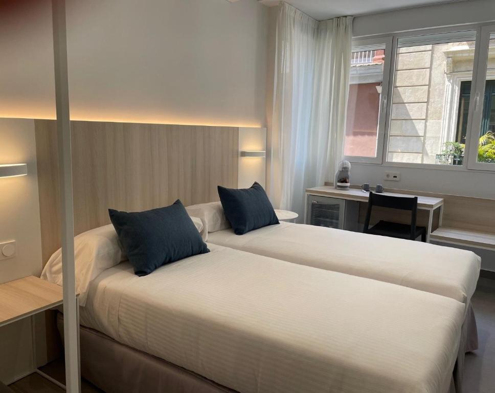 阿利坎特LC Hotel Urbano的酒店客房配有两张床和一张书桌