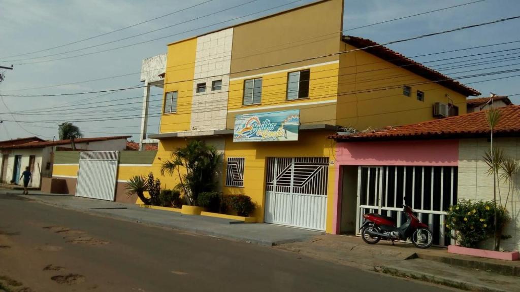 巴雷里尼亚斯Pousada Brilho dos Lençóis的一条街道旁的黄色建筑,有一辆摩托车