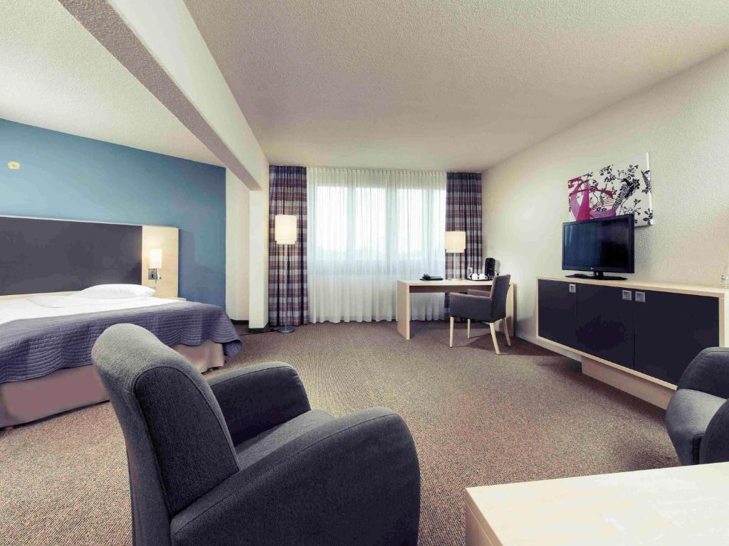 波恩波恩哈德伯格美居酒店的酒店客房,配有一张床、一张桌子和椅子