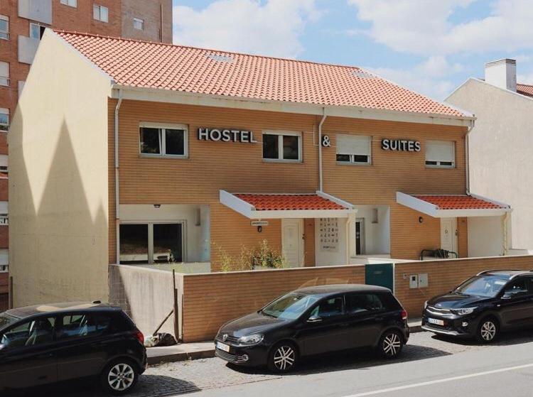 马托西纽什Oportocean Hostel的两辆汽车停在酒店门前的停车场