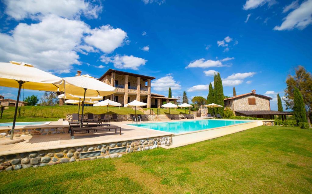 蒙特普齐亚诺Terra Antica - Resort, Winery & SPA的一个带遮阳伞的游泳池和一个房子