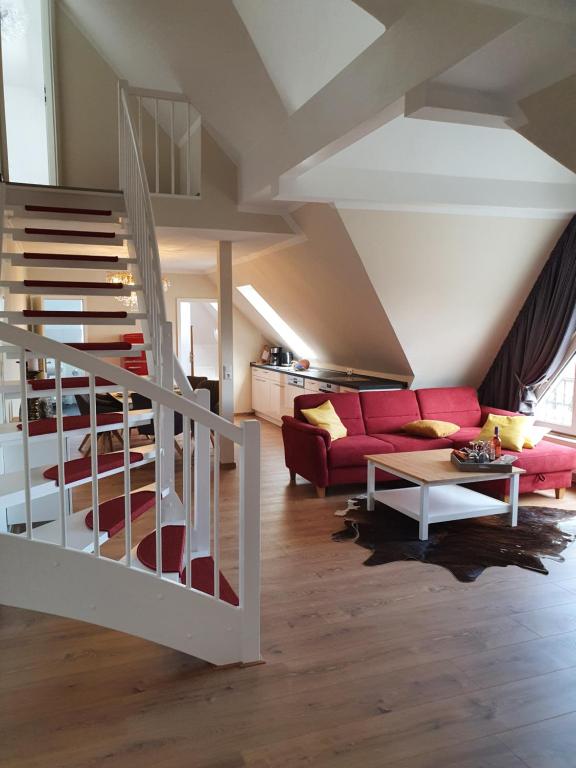 奥斯特巴特宁哈根Ostseestrand-Apartments的一间带红色沙发的客厅和楼梯