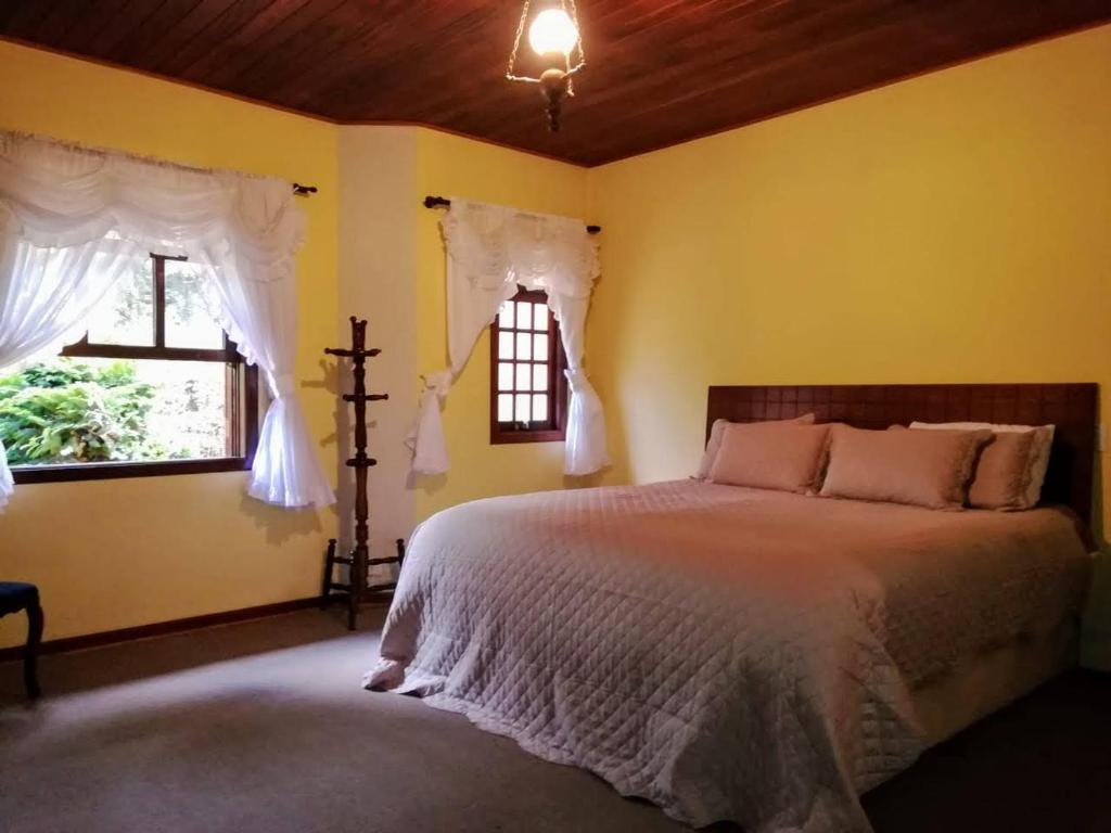 坎波斯杜若尔当Pequeno Paraiso的一间卧室设有一张床和两个窗户。