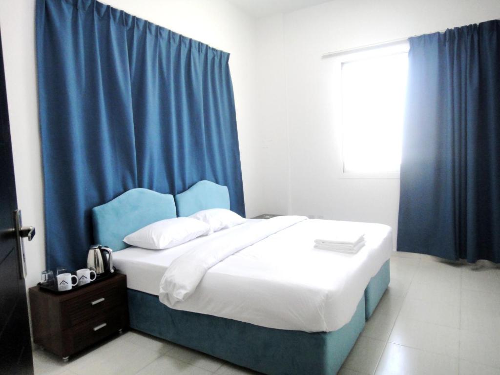迪拜Al Badaa Star Residence - Home Stay的一间卧室配有一张带蓝色窗帘的大床