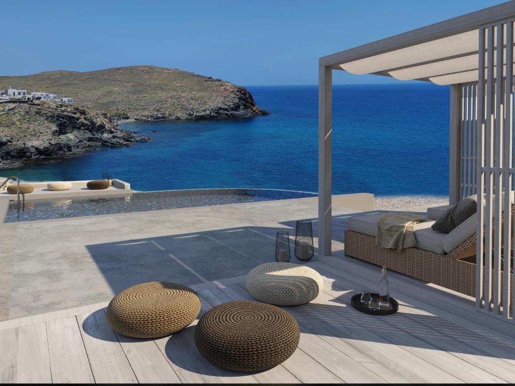 Merchia BeachThe Mykonist Merchia Beach Villas & Suites的一个带一张床和椅子的庭院和大海