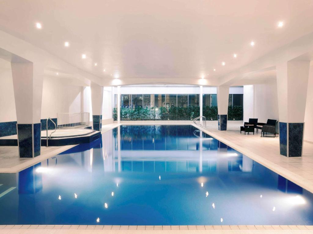 卡迪夫卡迪夫荷兰屋Spa美居酒店的大楼内一个蓝色的大型游泳池
