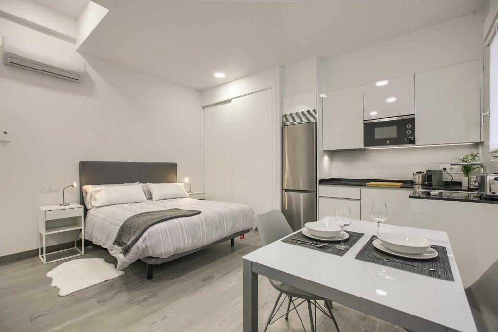 马德里RiNa MADRID apartamento 2的一间卧室配有一张床铺和一张桌子,还设有一间厨房