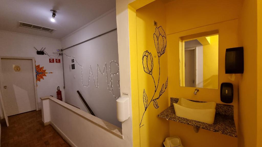 圣保罗Lamparina Hostel的浴室设有黄色墙壁、水槽和镜子