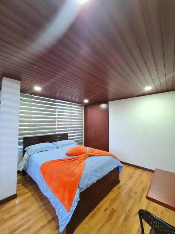 波哥大Hotel Casa Huesped Kiwi的一间卧室配有一张带橙色毯子的大床