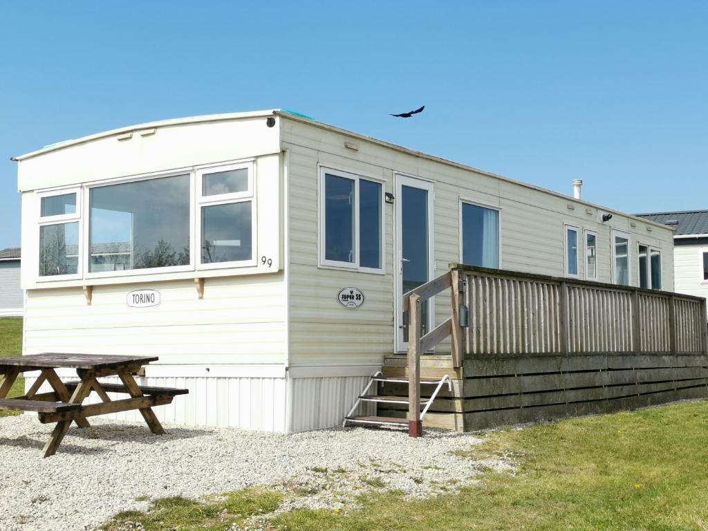 PoundstockNo99 Static Caravan Widemouth Fields 3 mins from beach的前面有一张野餐桌的小房子