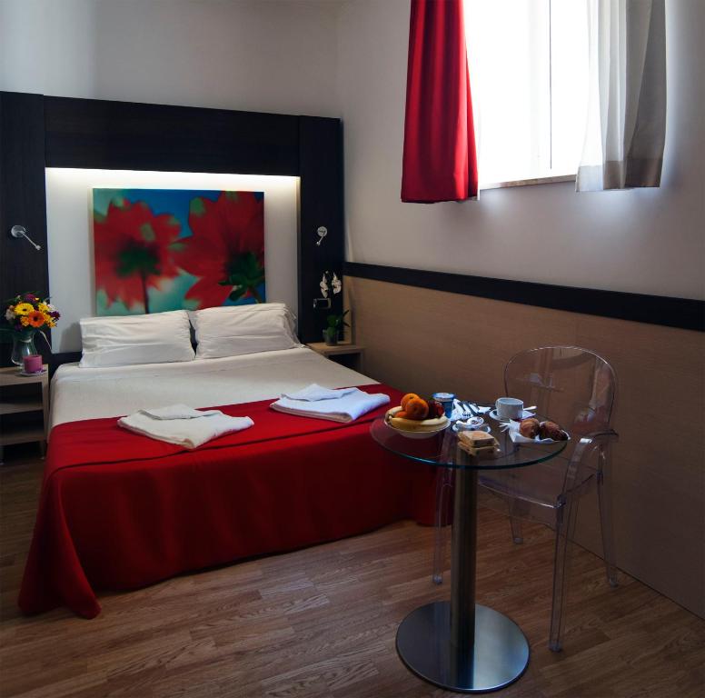 罗马路易斯安那酒店的一间卧室配有一张带红色毯子和桌子的床。
